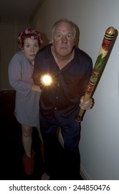 Older Couple - Man With A Bat And Woman With Hair In Curlers - Aroused From Bed In Pajamas Responding To Noises At Night.