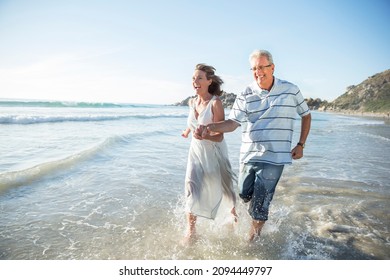 Older couple playing in waves on beach - Powered by Shutterstock