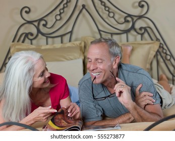 Older Couple Reading On Bed