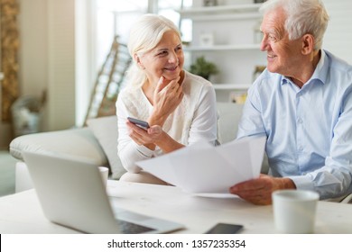 Older Couple Reading Papers Together On Sofa
