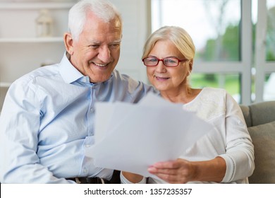 Older Couple Reading Papers Together On Sofa
