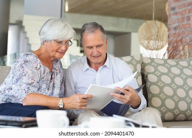 Older Couple Reading Papers Together On Sofa