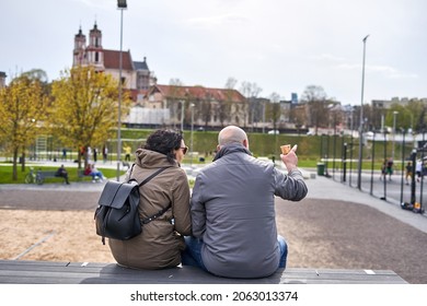 An Older Couple Is Sitting And Watching Overs Outdoor Sports Ground. 