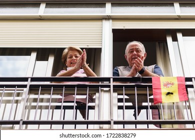 Older Couple In Spain Clapping In The Window In Support Of People Who Fight Against The Coronavirus