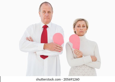 Older Couple Standing Holding Broken Pink Heart On White Background