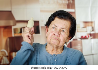 Older Cute Hispanic Woman In Blue Sweater Holding Up A Rolling Pin.