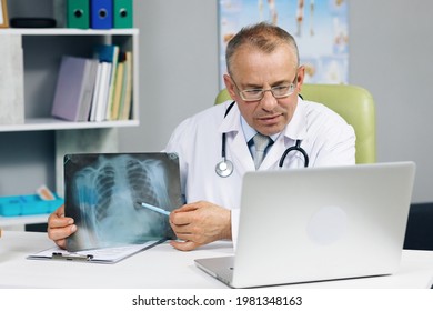 Older Doctor Talking To Patient Making Video Call On Laptop. Senior Male Physician Speaking Looking At Pc Screen Communicating By Webcam In Web Chat Consulting Client Online