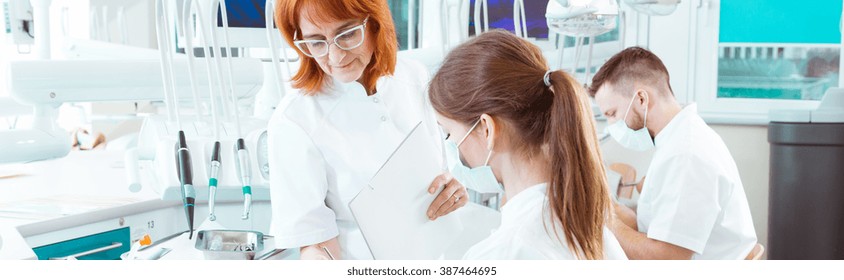 Older Experienced Stomatology Professor Checking Her Students' Work During Practical Exam