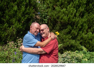 An Older Gay Married Couple In Love Embrace Outdoors In Summer.