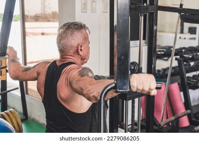 An older german guy does a set of reverse pec deck flyes. Working out upper back and rear delts at the gym.