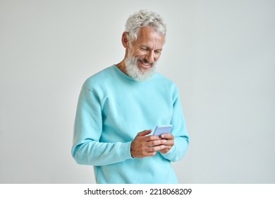 Older Happy Senior Bearded Stylish Hipster Man Holding Cell Phone Looking At Cellphone Using Smartphone Checking Mobile Apps News Or Communicating Online Standing Isolated On White Wall.