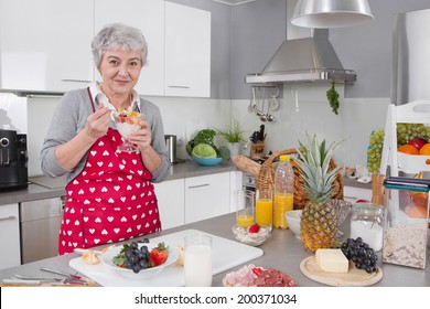 Older Happy Woman Eating Yogurt In The Morning With Fresh Fruits.