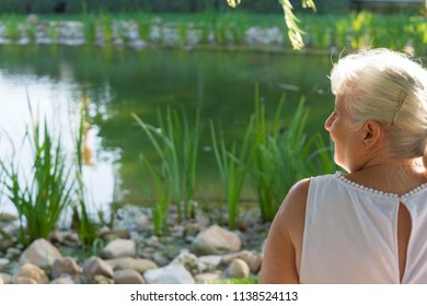 Older Lady Sitting By The Lake At The Park