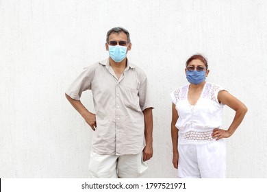 
Older Latino Couple With Protective Face Masks On White Wall Background, New Normal Covid-19