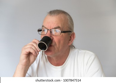 Older Male Drinking Expresso Coffee From Small Black Cup. Wearing Glasses. White Background In Studio