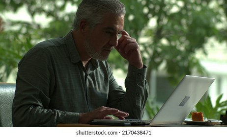 Older male entrepreneur working in front of laptop comuter sitting at coffee shop
