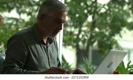 Older male entrepreneur working in front of laptop comuter sitting at coffee shop
