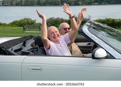 Older Male LGBT Gay Couple Enjoying  A Sunny Day And Driving In Their White Convertible With The Top Down.  The Couple Is Smiling And Happy.