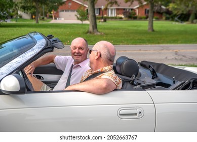 Older Male LGBT Gay Couple Enjoying  A Sunny Day And Driving In Their White Convertible With The Top Down.  The Couple Is Smiling And Happy.