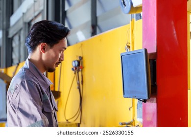 Older male mechanic inspecting vehicle undercarriage in repair shop. Wearing grey uniform with reflective strips. Pointing at car parts, demonstrating focus and expertise in auto maintenance. - Powered by Shutterstock