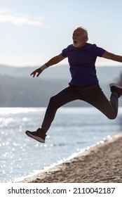 Older Man With Beard In Sportswear Jumping On The Beach