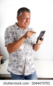 Older Man Between 45 And 50 Years Old Pointing At The Cell Phone Smiling.