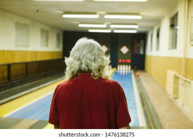 An Older Man Bowling In A Bowling Alley