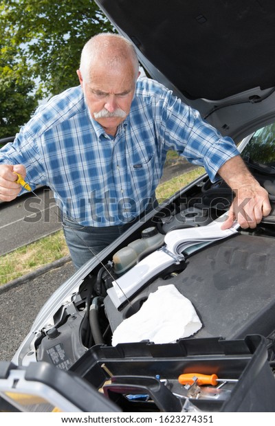 older man\
checking levels and servicing his\
car