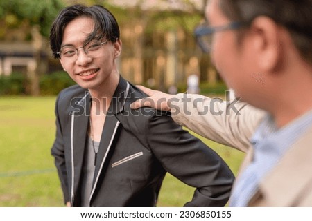 An older man commends his protege for a good job. A younger man openly praised and congratulated by his mentor or boss while at the city park. Or a dad proud of his son.