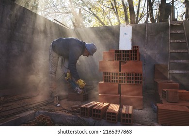 Older Man Cutting Brick With Grinder And Generating Dust