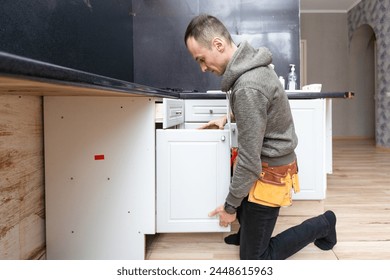 Older man disassembling apartment kitchen out of service