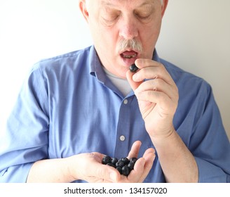 An Older Man Eating A Blueberry While Holding A Handful