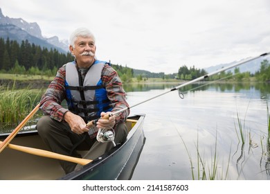 Older man fishing in canoe in still lake - Powered by Shutterstock