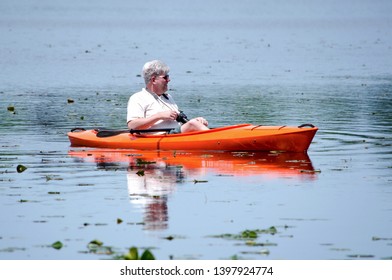 An Older Man Gets Healthy Exercise In A Orange Kayak