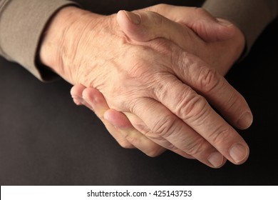 An Older Man Grasps His Hand On A Black Background With Copy Space.