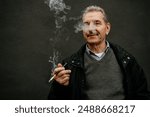 An older man with grey hair and a mustache is smoking a cigarette against a grey wall.