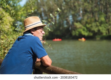 Older Man In Hat Observing Children With Canoe On A Reservoir. Canal De Castilla. Spain.