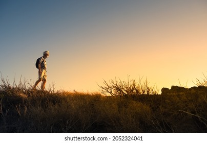 Older Man Hiking Backpacking Through The Countryside. People Adventure Active Lifestyle Concept. 