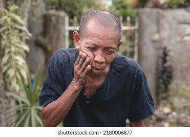 An Older Man In His Early 60s Suffering From A Throbbing Molar. Applying Pressure To Relieve Pain. Experiencing A Bad Toothache Or Dry Socket While Outside.