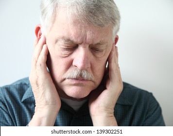 Older Man Holds Both Hands To His Upper Jaw Near The Ears