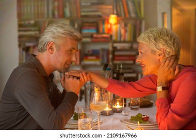 Older Man Kissing Hand Of Wife At Romantic Dinner