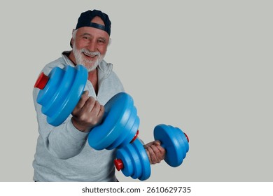 An older man laughs while training with blue dumbbells. Strong and active, he lives his motto, Staying fit with age. Joy and movement go hand in hand.