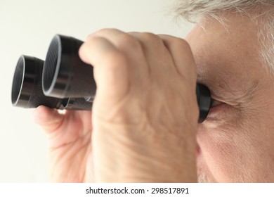 An Older Man Looking Through An Old Pair Of Binoculars