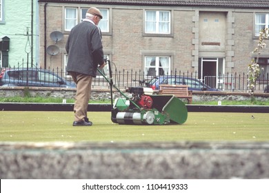 Older Man Mowing A Bowling Green