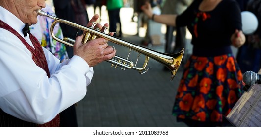 older man playing trumpet. Jazz Musician with Flugelhorn on street background. 