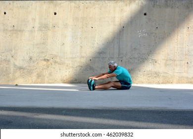 Older Man Practicing Stretching On The Street.