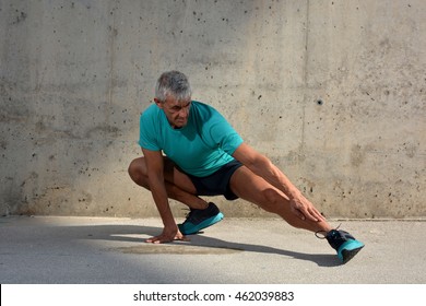 Older Man Practicing Stretching On The Street.