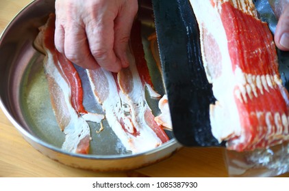 An Older Man Prepares Bacon For Frying