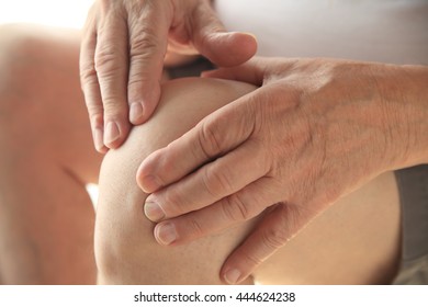 Older Man Puts Both Hands On An Aching Knee.