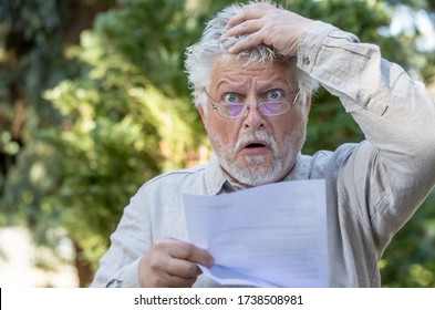 An Older Man Reads A Letter And Is Horrified. He Wears Glasses.